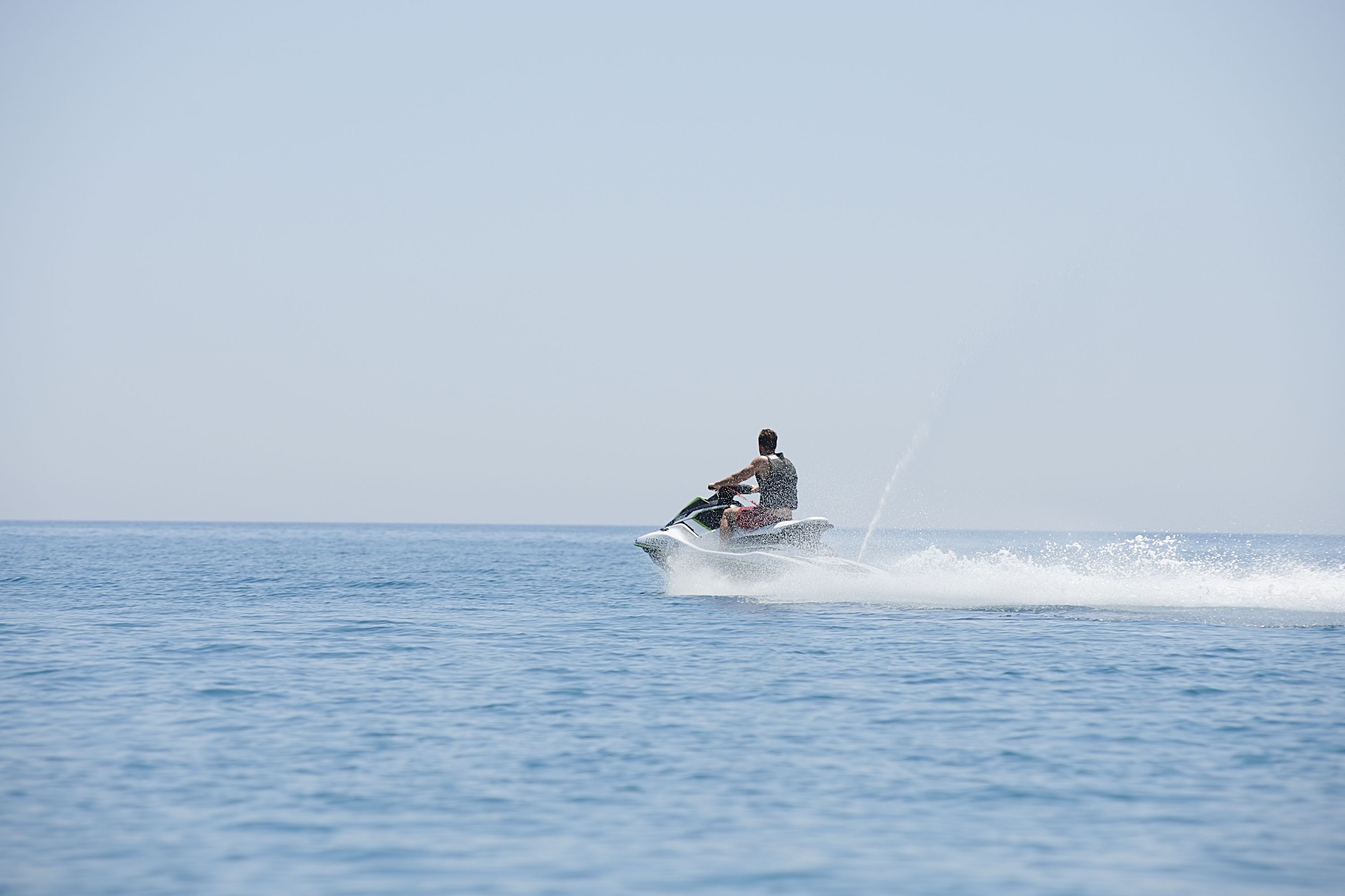 A person jet-skiing on a calm body of water.