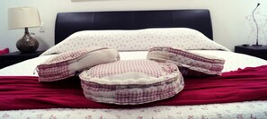 Una cama con una manta roja, una almohada y una mesita de noche con una lámpara.