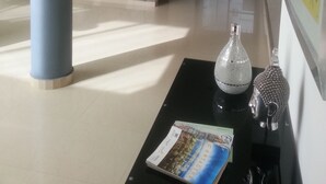 A spacious lobby with a stone wall, a large column, a staircase, and a statue on a black table. - Casa Blanca del Mar Hotel Boutique (Cartagena)