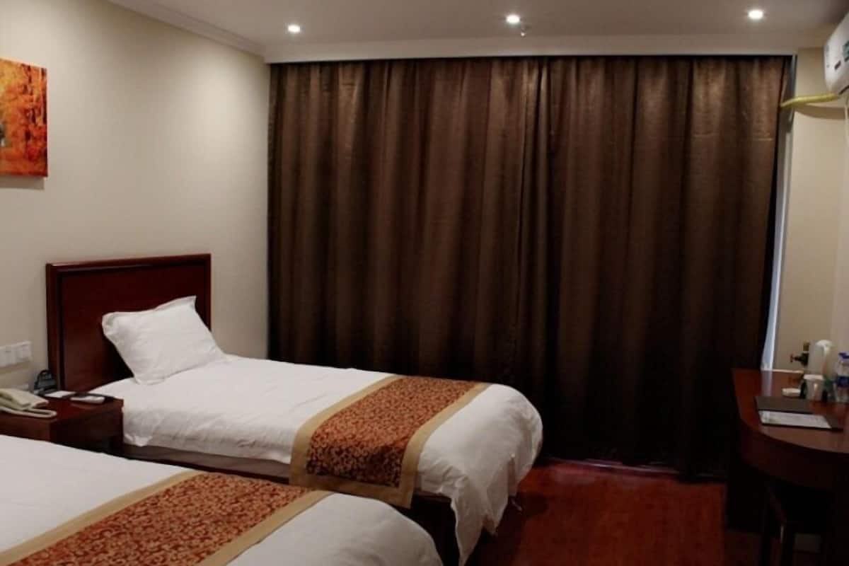A hotel room with two beds, a desk, a chair, a telephone, and a window with curtains.