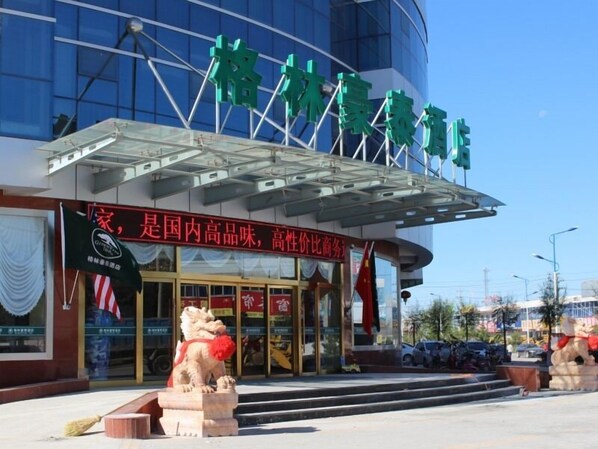 A hotel with a modern glass facade, a prominent entrance with a lion statue, and a signboard with Chinese characters.