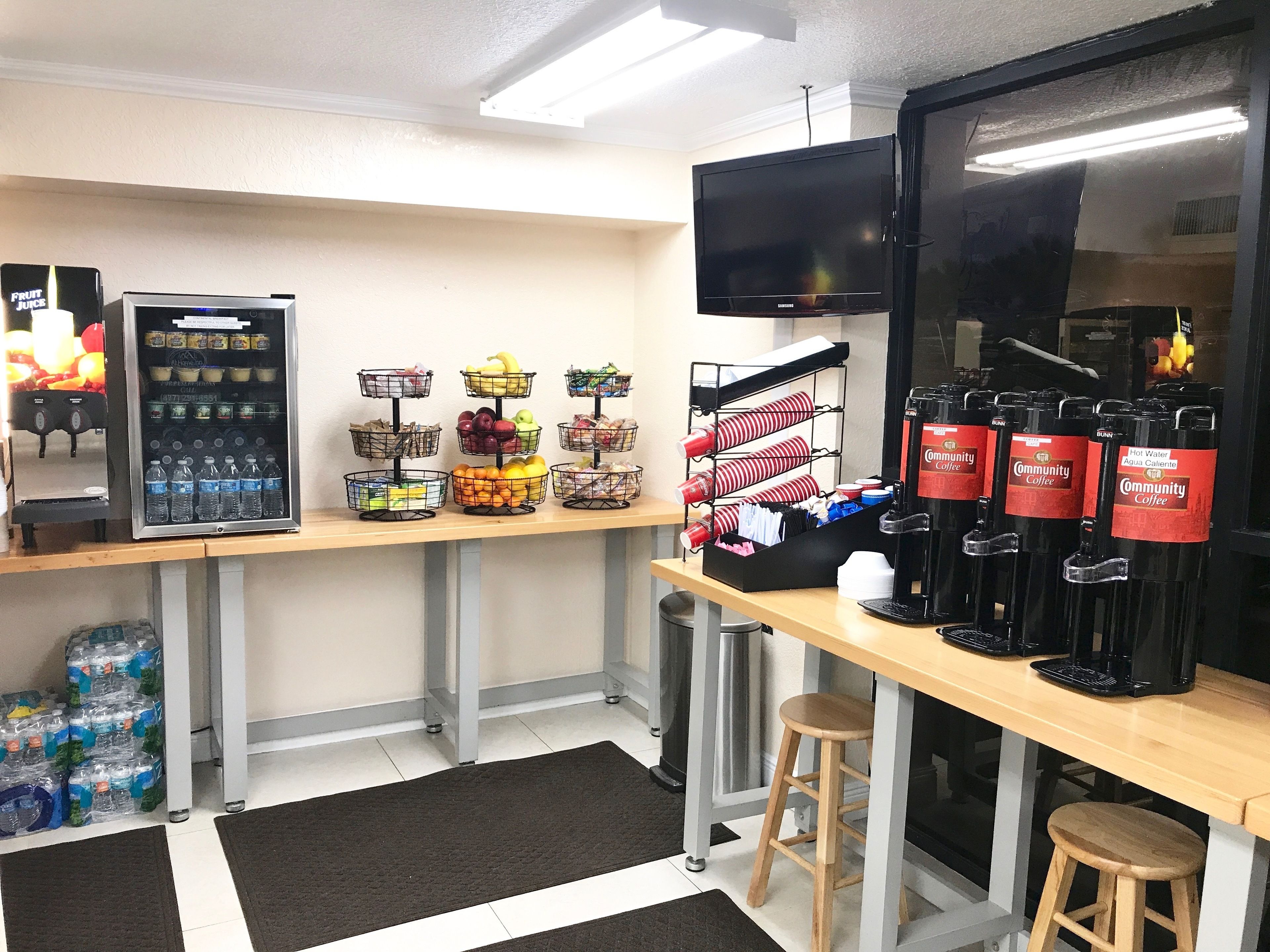 Ein Café-Interieur mit einem Getränkespender, einer Kaffeemaschine und einem an der Wand montierten Fernseher.