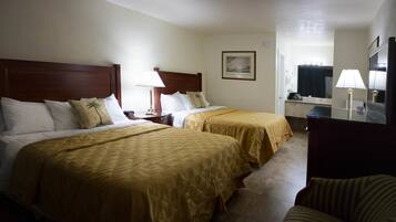A hotel room with two beds, a desk, a chair, a mirror, and a bathroom visible through an open door.