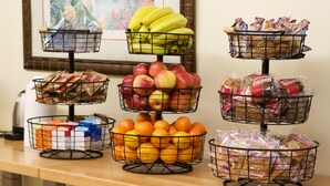 A buffet table with various food items including fruits, bread, and packaged snacks.