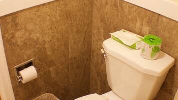 A bathroom with a toilet, a trash can, and a toilet paper holder.