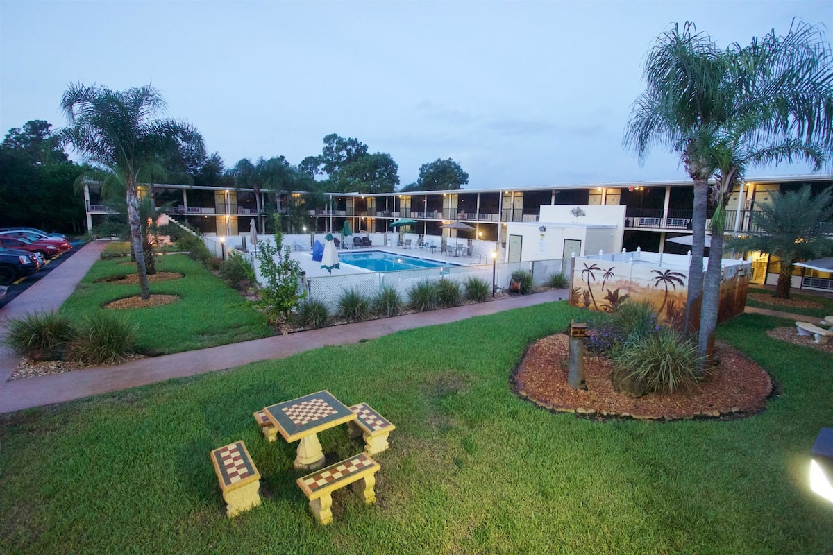 Un hotel con piscina, zona de estar exterior y césped bien cuidado.