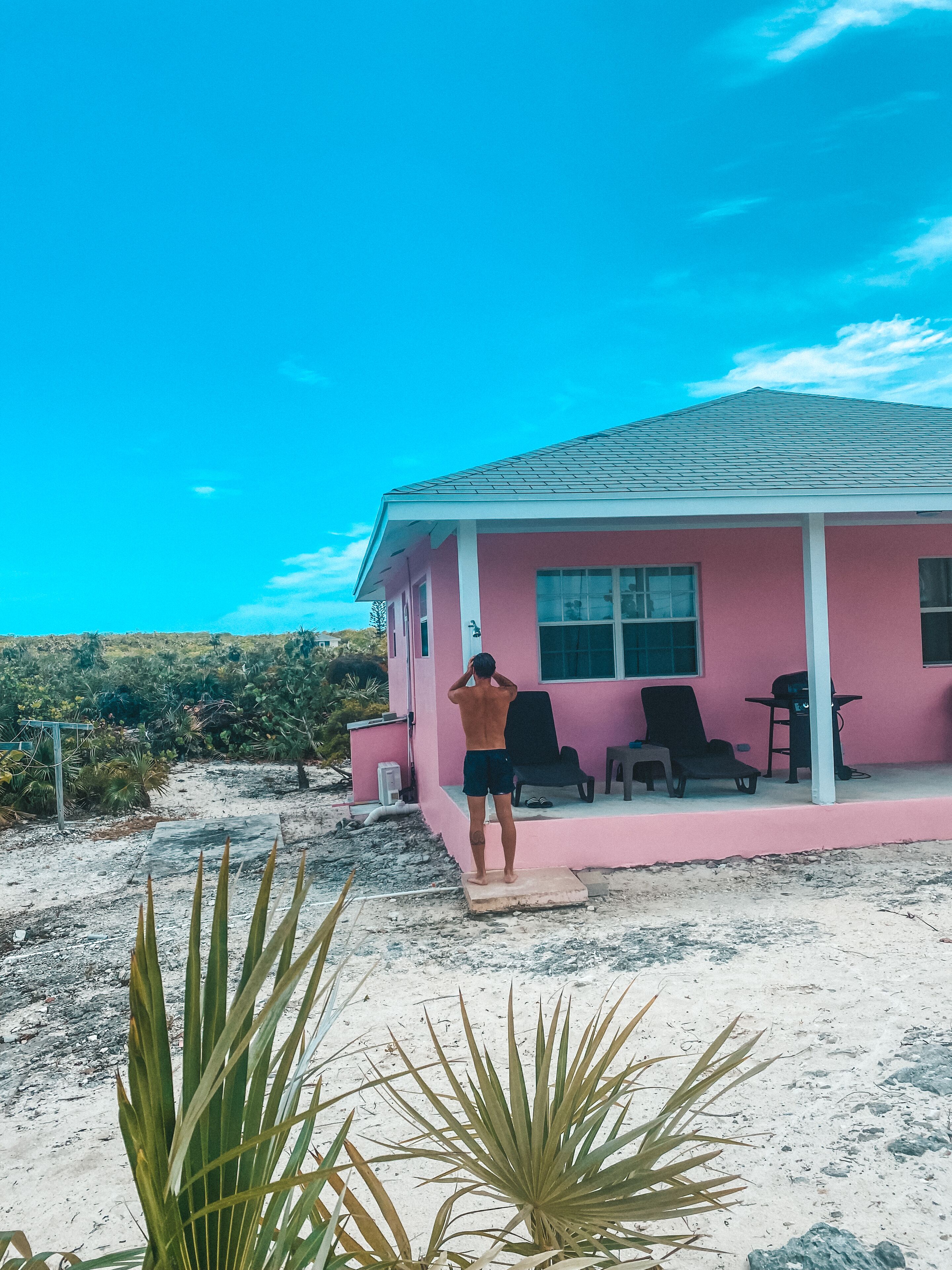 A pink house with a person standing on a porch.