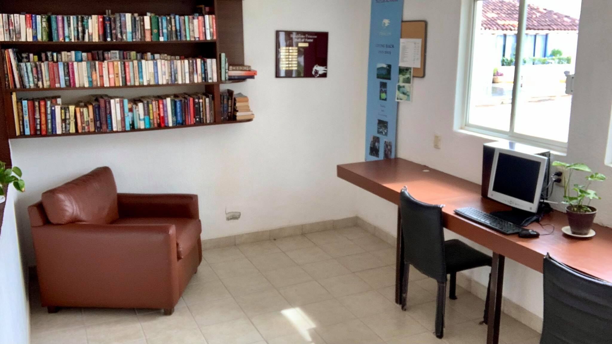 A small office with a desk, computer, and a bookshelf filled with books.