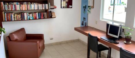 A small office with a desk, computer, and a bookshelf filled with books.