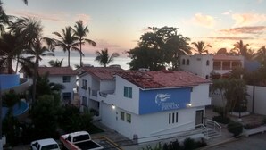 A building with a sign reading "Bungalows Princess" and a view of the sea in the background. - Suites Princess (Bucerías)