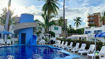 Een buitenzwembad, parasols bij het zwembad en ligstoelen