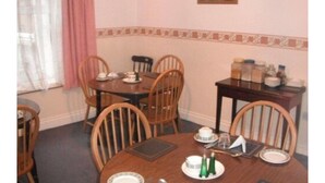 Comedor con una mesa redonda, seis sillas de madera y una mesita con condimentos.