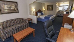 Una habitación de hotel con una cama, un sofá, un escritorio y una silla.