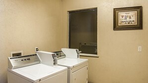 Un lavadero con dos lavadoras de carga frontal, una ventana y un cartel en la pared.