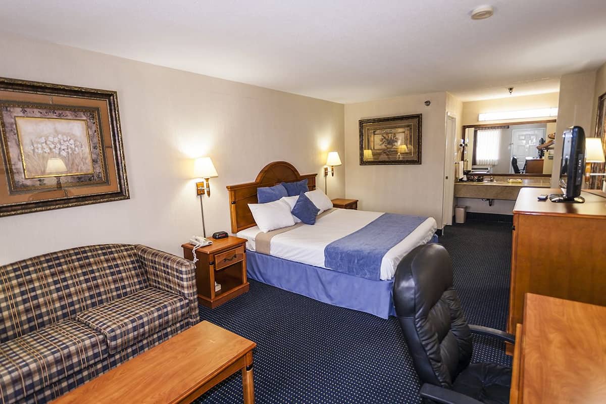 Ett hotellrum med en säng, en soffa, ett skrivbord och en stol.