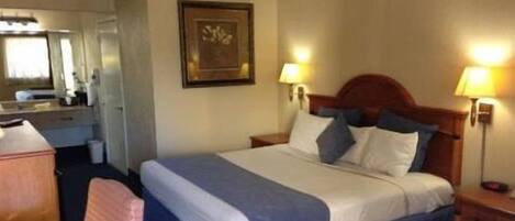 Una habitación de hotel con cama, lámparas de noche, escritorio y una silla.