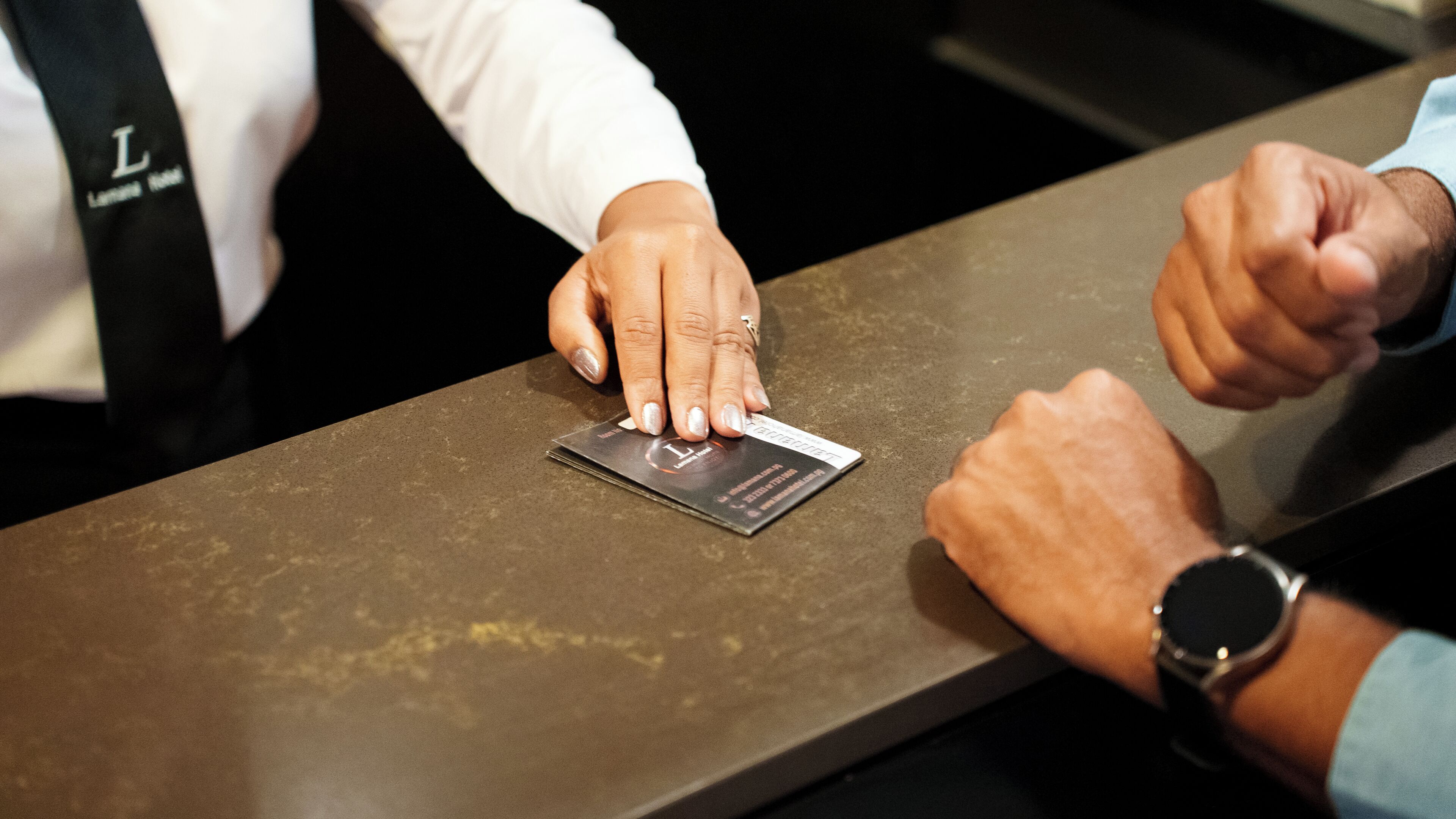 A person placing a business card on a metallic surface.