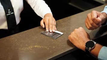 A person placing a business card on a metallic surface.