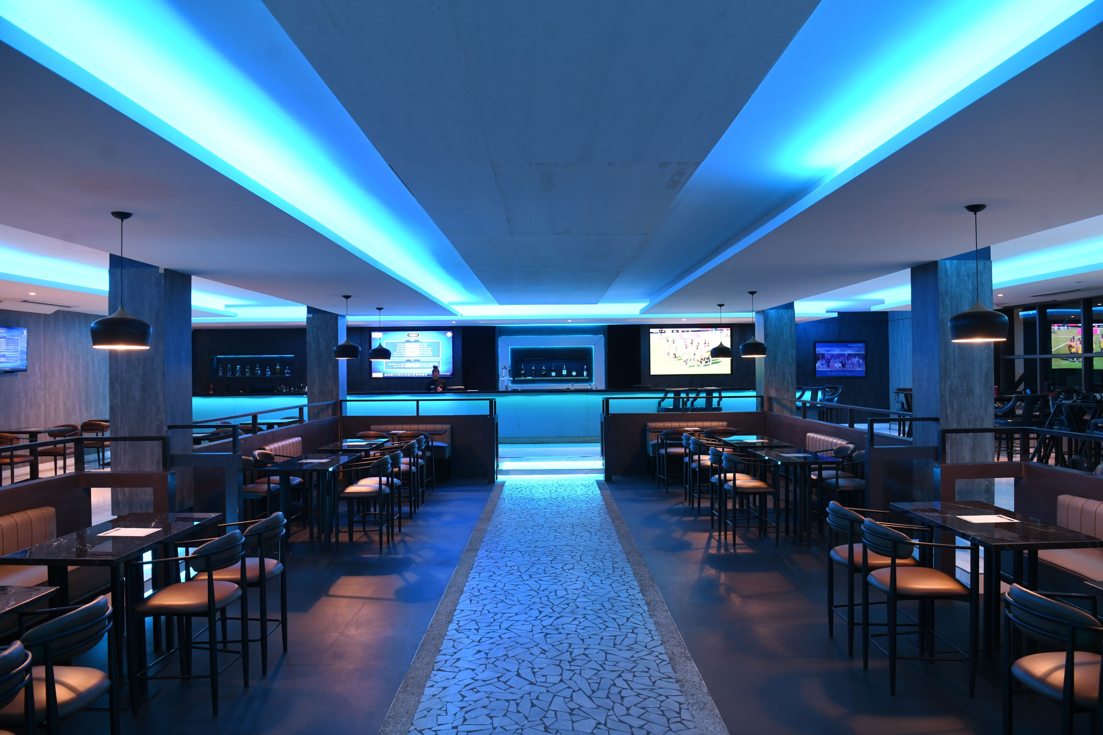 A modern bar area with seating, a patterned floor, and ambient lighting.