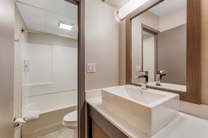 A modern bathroom with a bathtub, toilet, and a large sink with a mirror above it. - Red Roof Inn Bourbonnais (Bourbonnais)