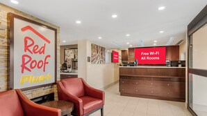 A hotel lobby with a reception desk, Red Roof Plus signage, and a Red Roof Plus Plus sign. - Red Roof Inn Bourbonnais (Bourbonnais)