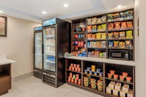 A snack and beverage section with a refrigerated display, microwave, and shelves stocked with snacks and drinks. - Red Roof Inn Bourbonnais (Bourbonnais)