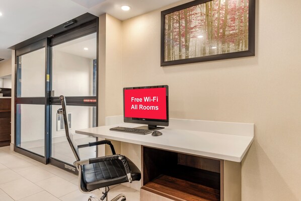 Un espacio de oficina moderno con un escritorio, una silla y un letrero que indica acceso a internet Wi-Fi gratuito.