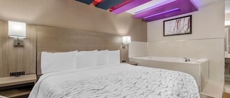 Una habitación de hotel con cama, mesita de noche, lámpara de pared y un cuadro.