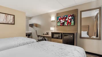 A hotel room with two beds, a flat-screen TV mounted on the wall, a desk with a chair, a microwave, and a refrigerator.