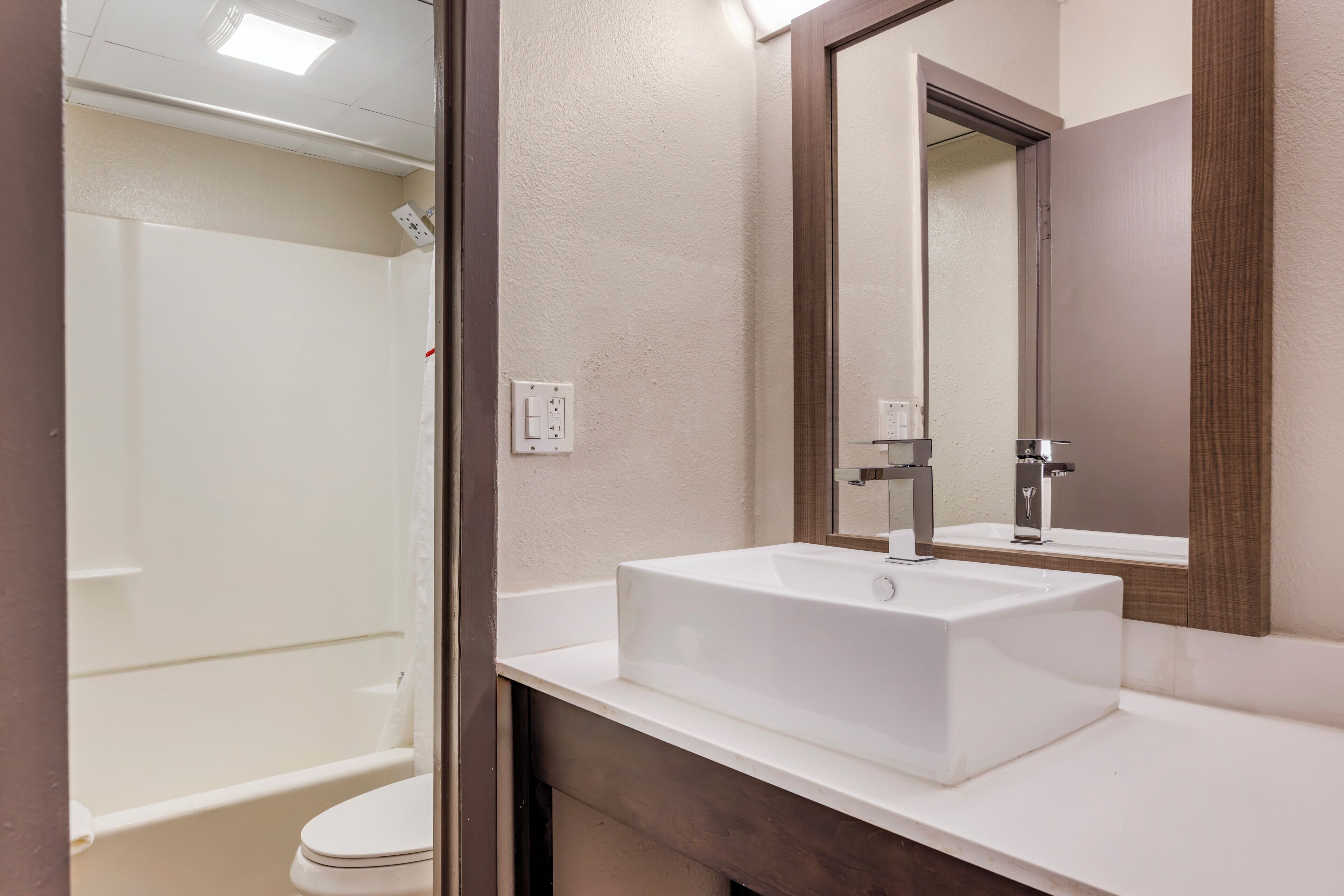 A modern bathroom with a white sink, a mirror, and a shower.