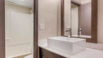 A modern bathroom with a white sink, a mirror, and a shower.
