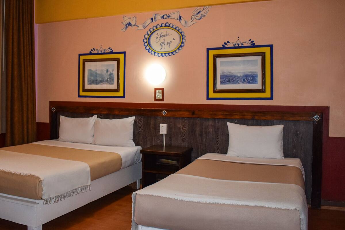 A hotel room with two beds, a wooden headboard, and a wall with framed pictures and decorative elements.