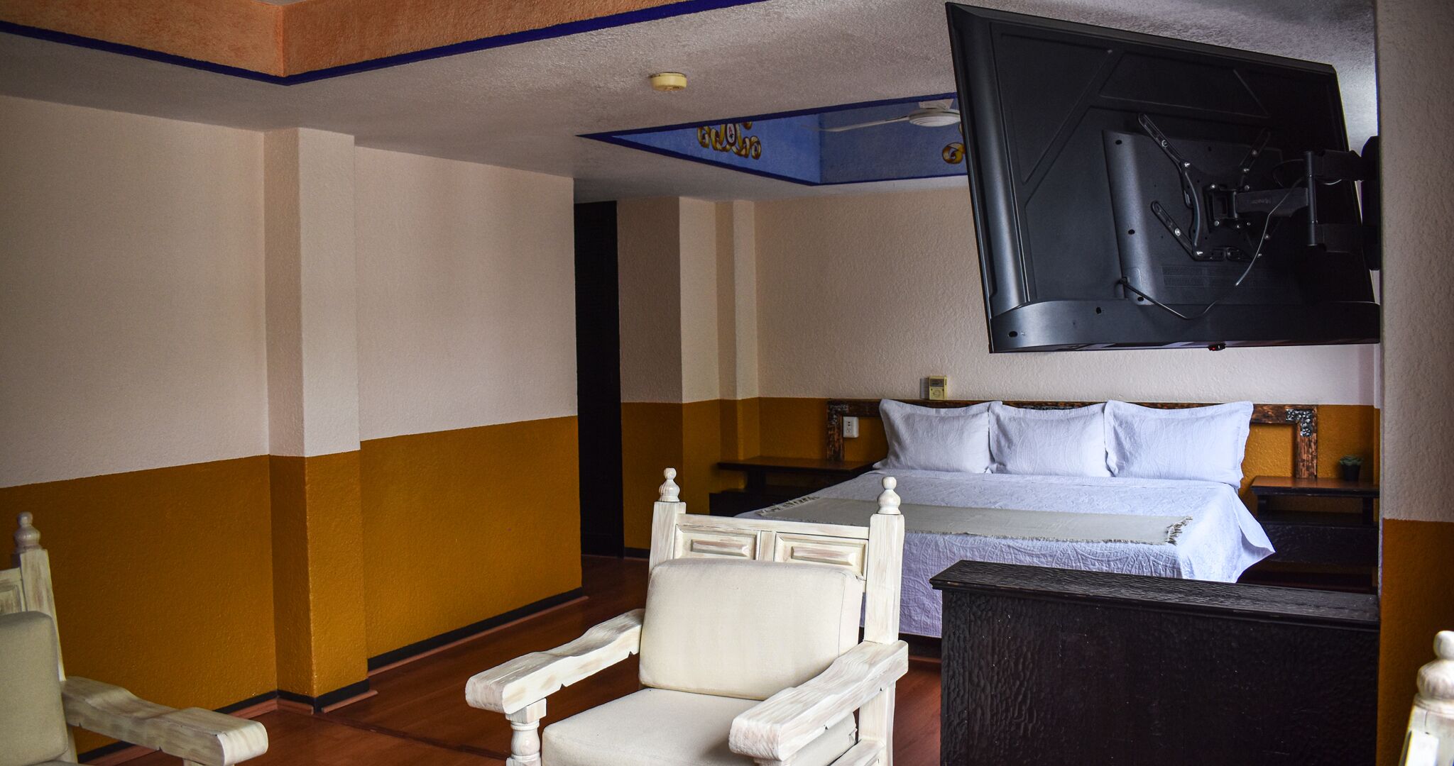 Ein Hotelzimmer mit einem Bett, einem Sessel und einem an der Wand befestigten Fernseher.