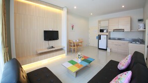 A modern living room with a flat-screen TV, a coffee table with a colorful geometric pattern, and a sofa with floral cushions. - The Icon Place at Central Pattaya (Pattaya)