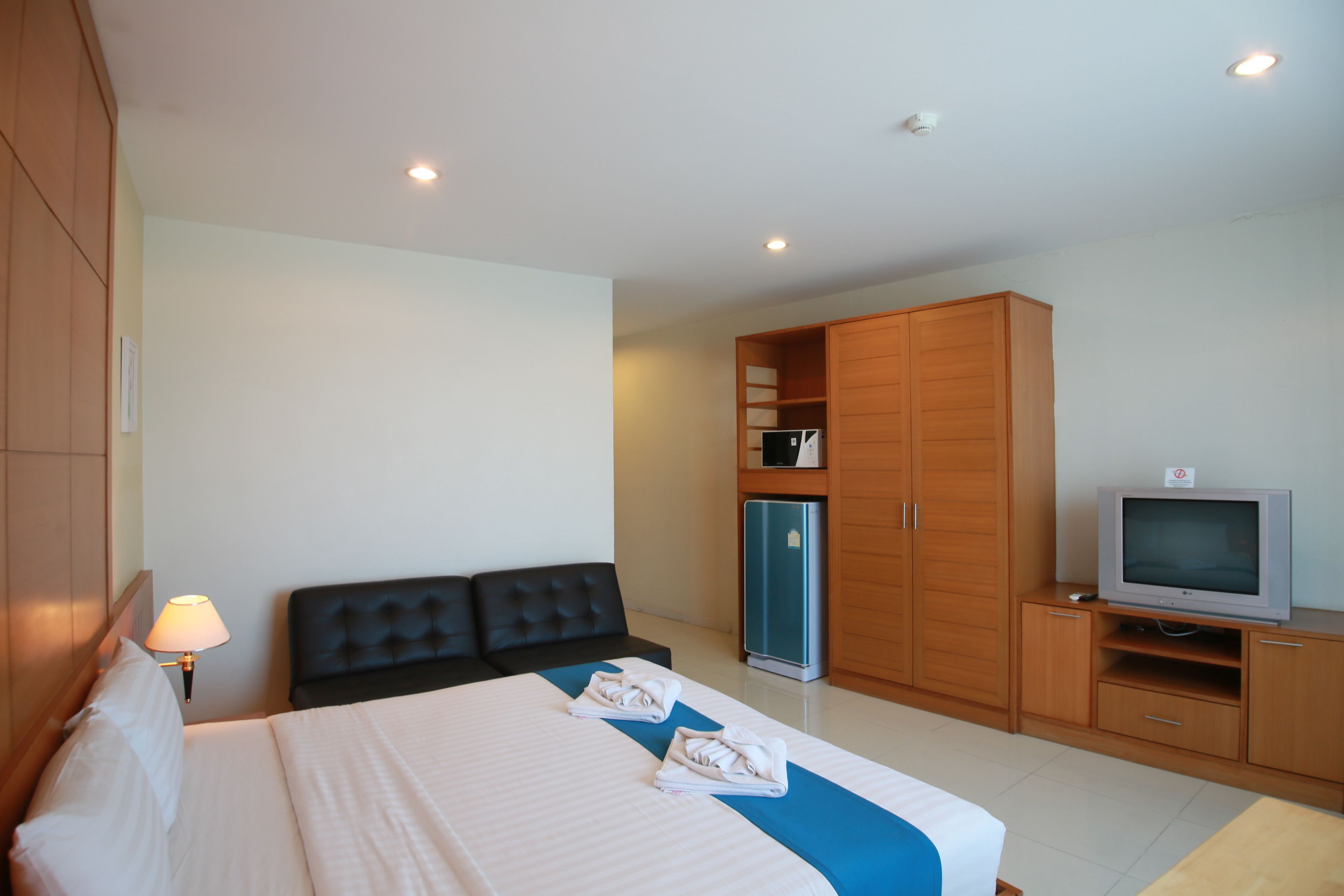 A hotel room with a bed, a TV, a wardrobe, and a refrigerator.