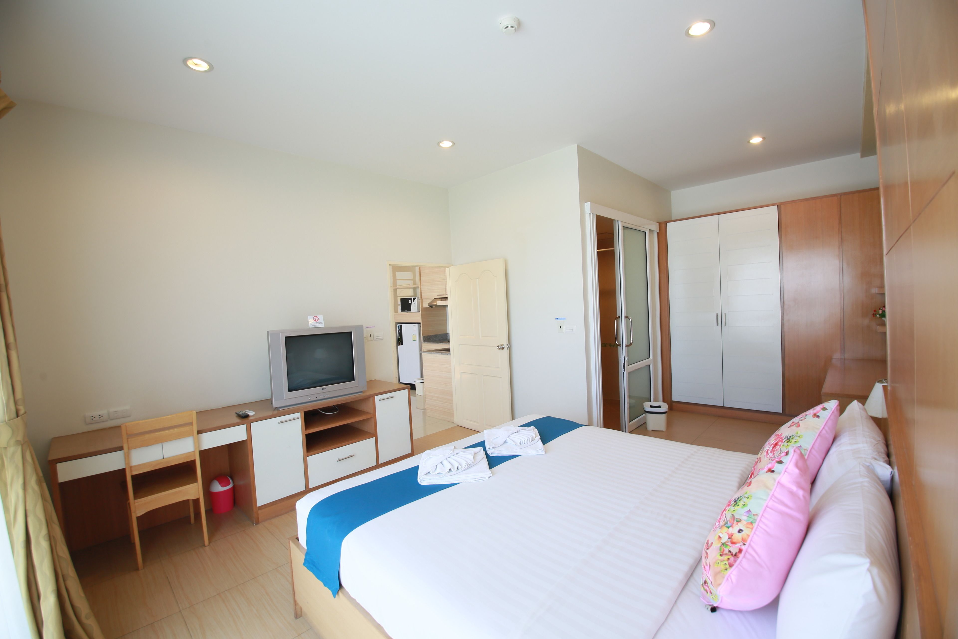 Una habitación de hotel con cama, escritorio con televisor, armario y baño.