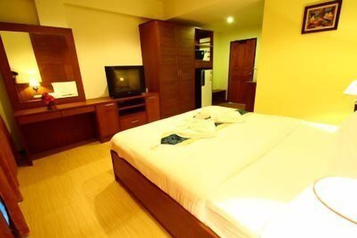 A hotel room with a bed, a TV, a desk, and a wardrobe.