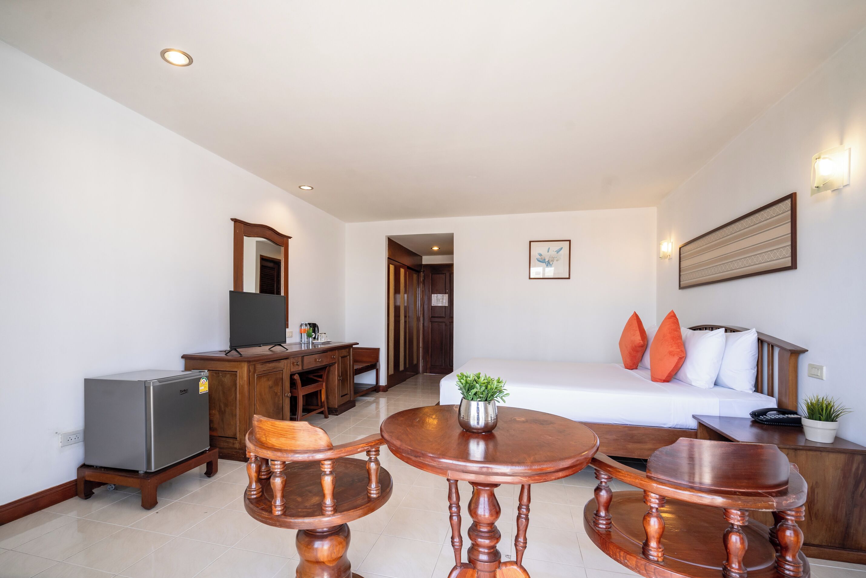 Una habitación de hotel con cama, escritorio, refrigerador, mesa de comedor y televisor.