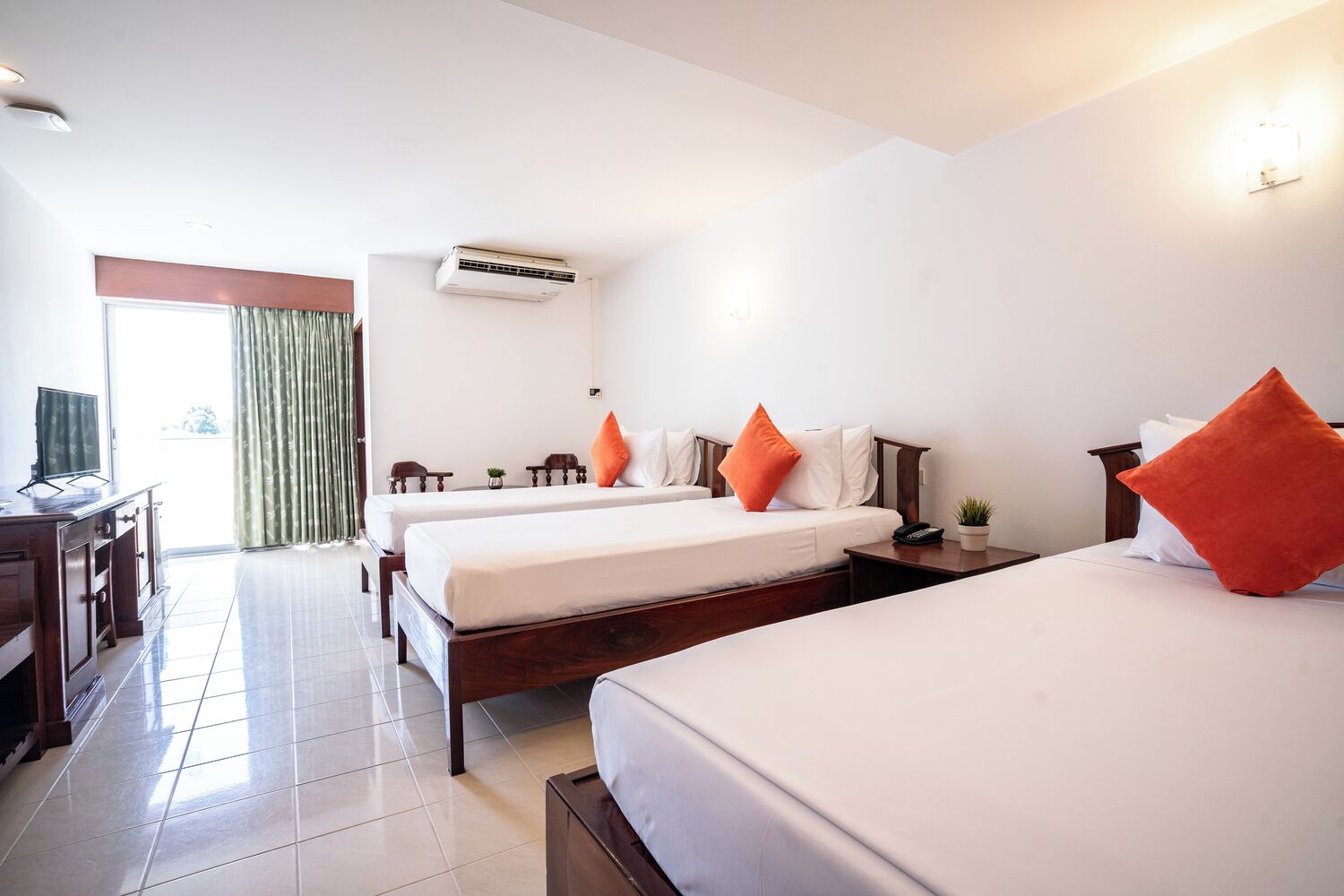 Quarto de hotel com duas camas, uma escrivaninha, ar condicionado e vista através de uma grande janela.