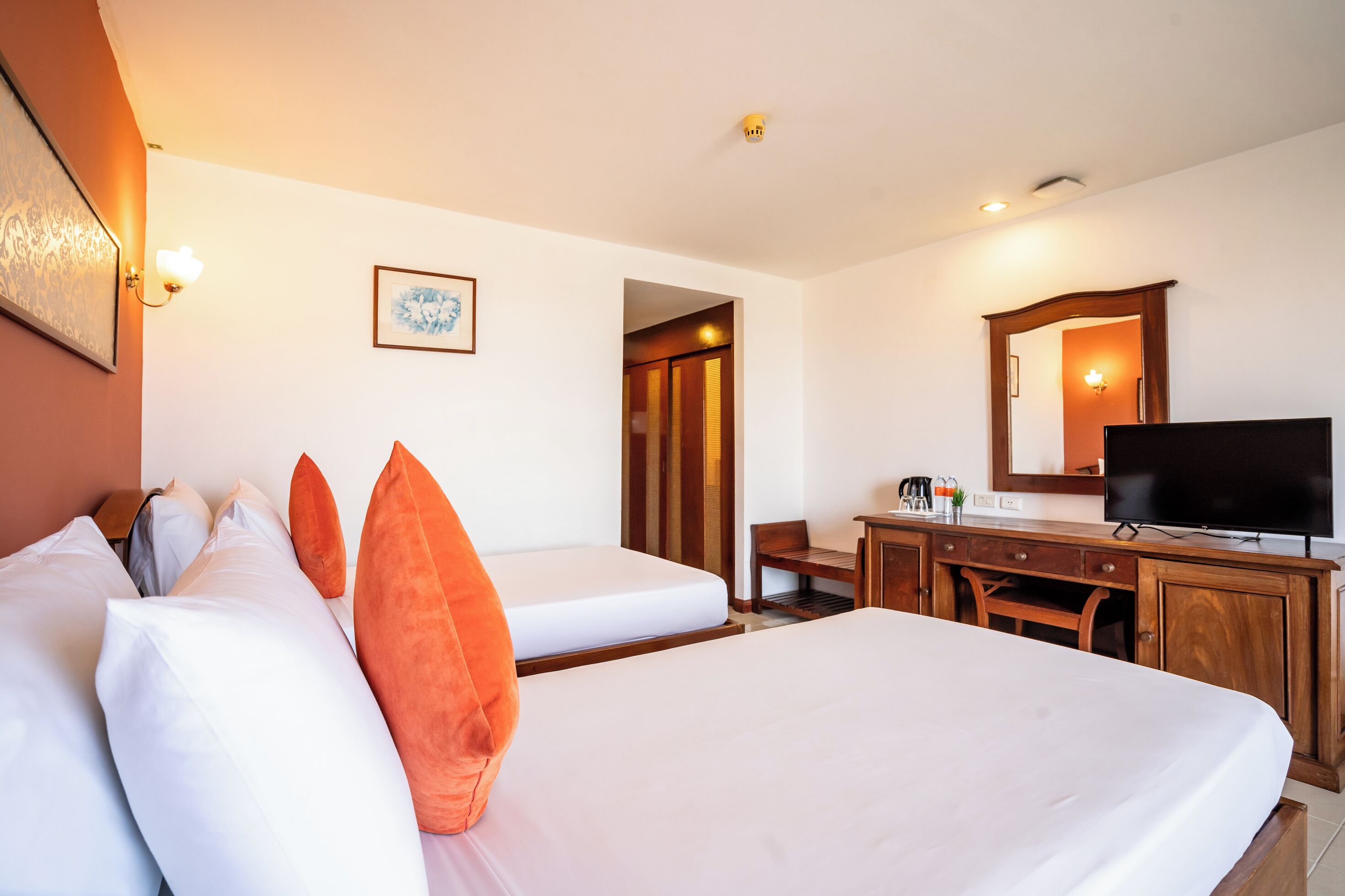 Ein Hotelzimmer mit zwei Betten, einem Schreibtisch, einem Fernseher und einer Badezimmertür.