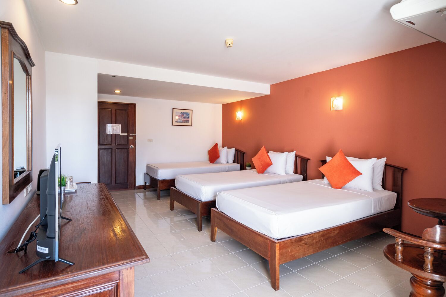 A hotel room with two beds, a wooden desk, a TV, and a small table.