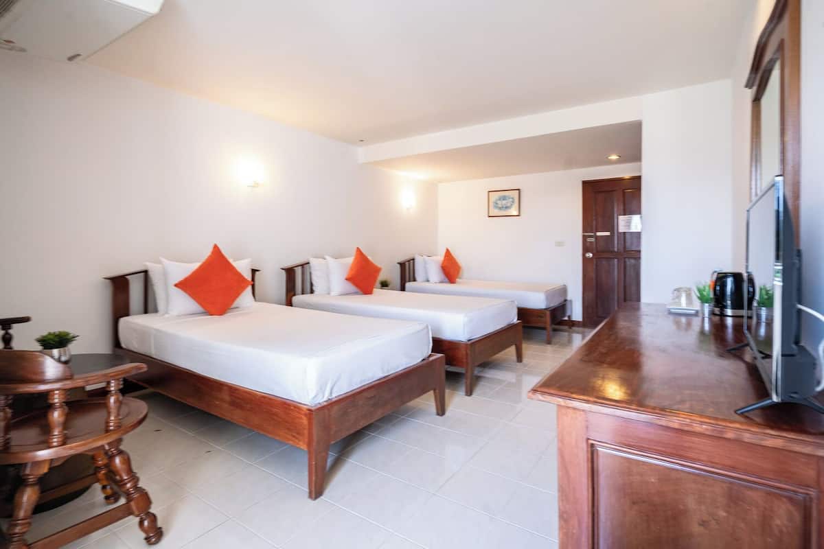 Una habitación de hotel con dos camas individuales, una mesa de madera, un televisor y una zona de kitchenette.
