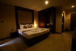 A hotel room with a large bed, bedside tables, a mirror, and a door leading to another room. - Honey Inn (Pattaya)