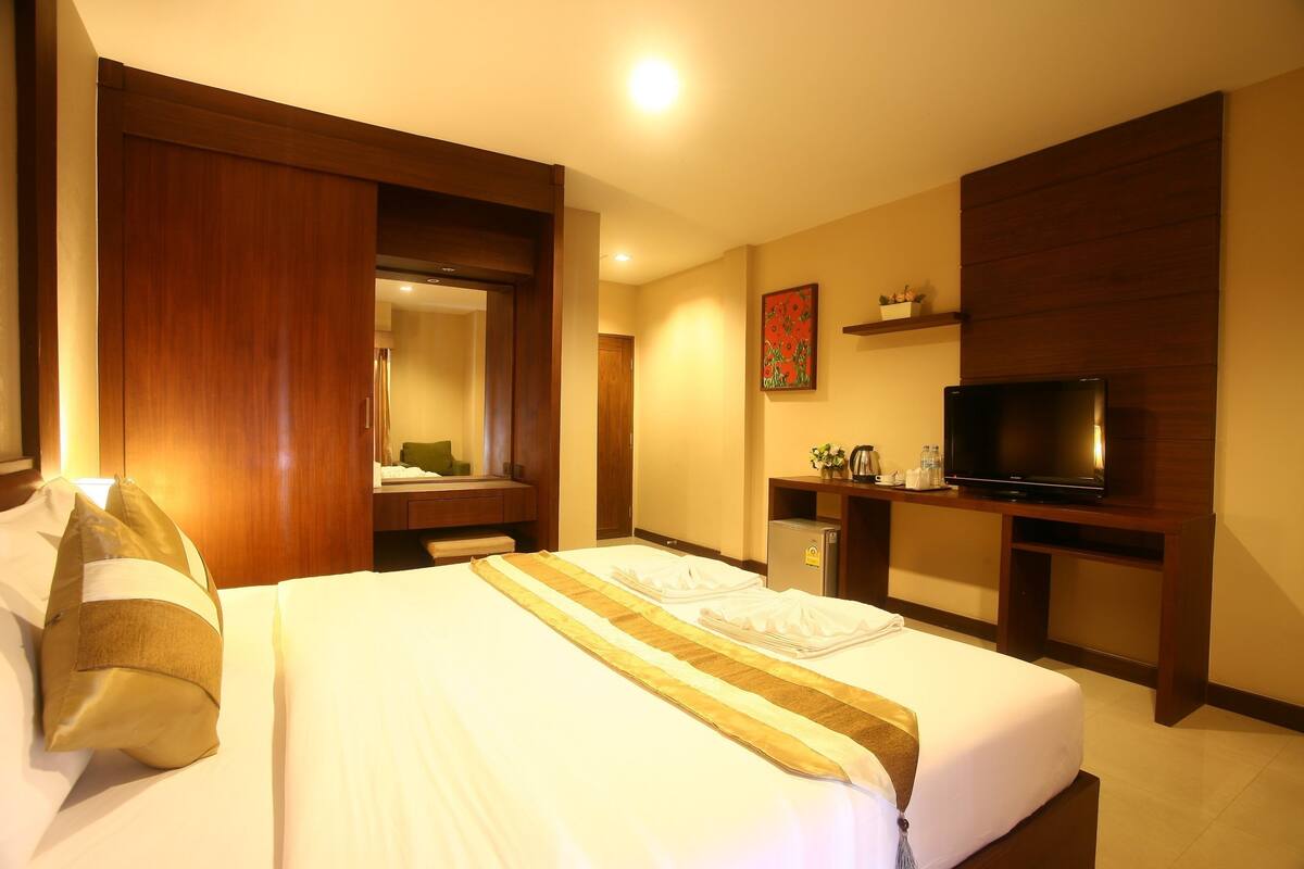 Ein Hotelzimmer mit Bett, Fernseher, Schreibtisch und Spiegel.