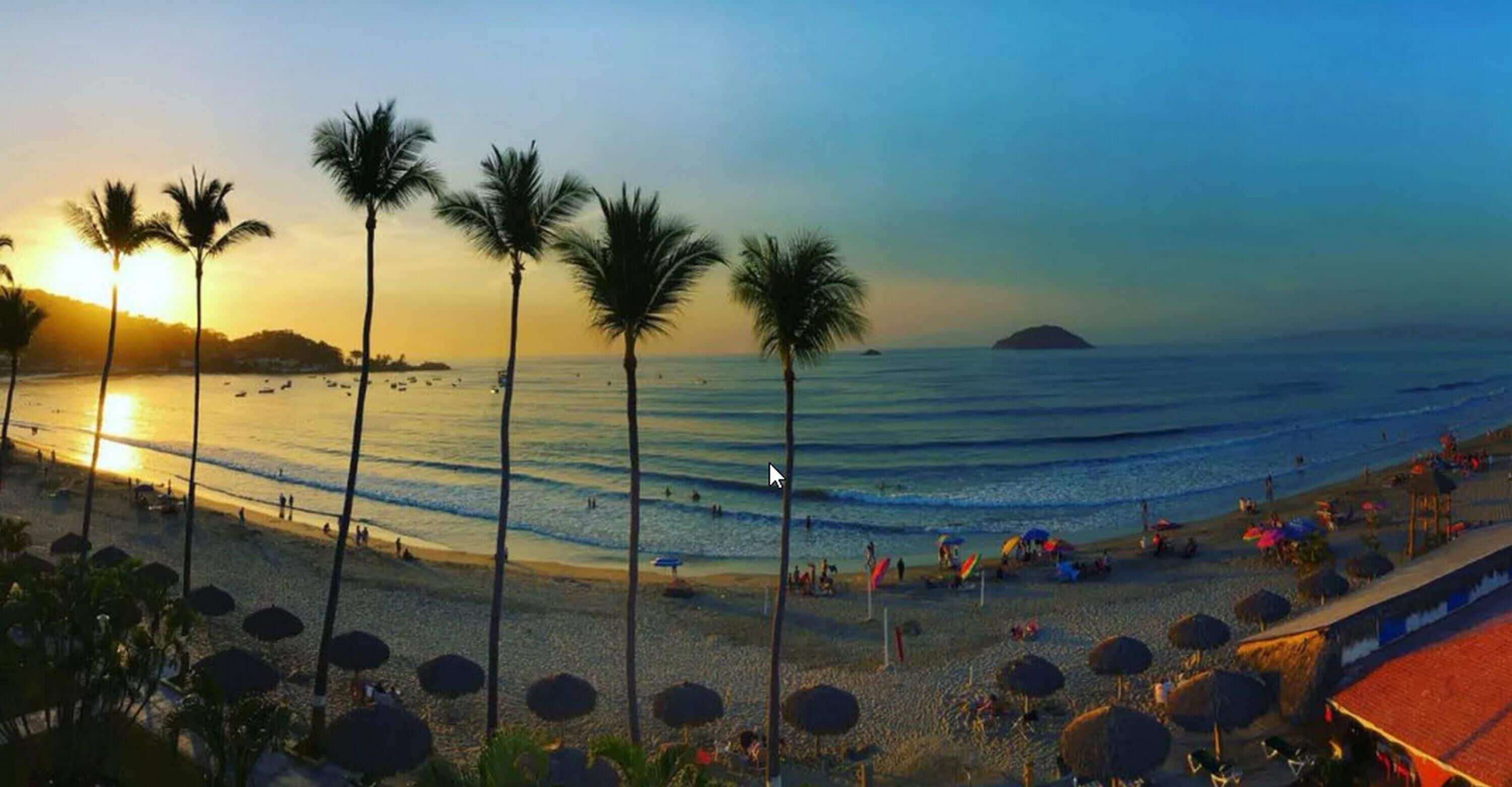 Una playa con palmeras, sombrillas y una puesta de sol.