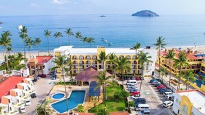 Un hotel con varios balcones, piscina y vistas al mar.