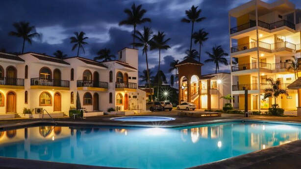 Un hotel con piscina, palmeras y un exterior bien iluminado al atardecer.