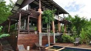 Ein Holzhaus mit Schwimmbad, umgeben von viel Grün.