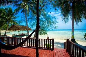 A wooden deck with a hammock, overlooking a beach with palm trees and a thatched-roof hut. - Salad Villa (Ko Pha-ngan)