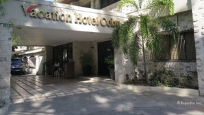 Das Hotel Vacation Hotel Cebu mit einer Steinfassade, einem überdachten Eingang und Blumentöpfen.